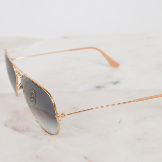 Aviator sunglasses with gold frame on a marble surface