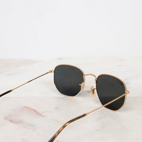 Sunglasses with gold frame and black lenses on a marble surface
