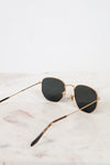Sunglasses with gold frame and black lenses on a marble surface