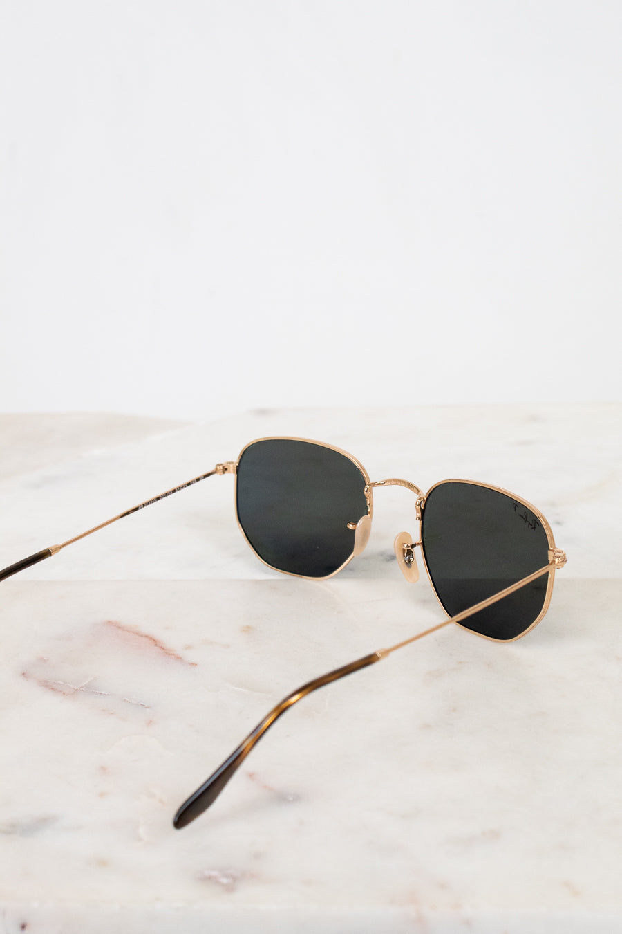 Sunglasses with gold frame and black lenses on a marble surface