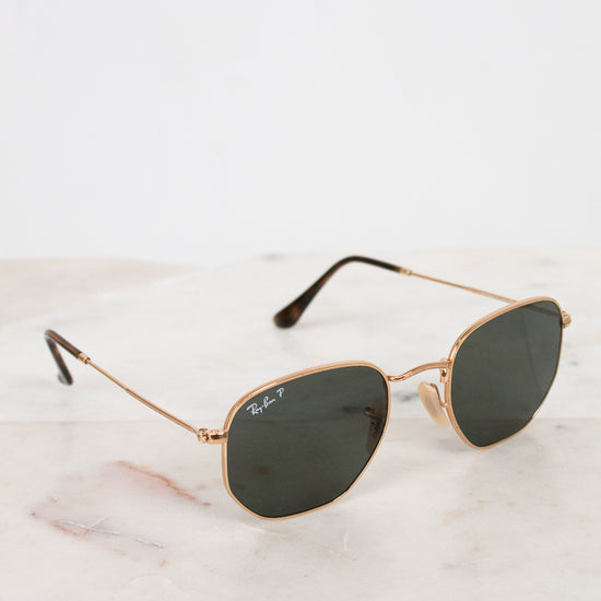 Gold-framed sunglasses with dark lenses on a marble surface