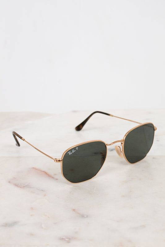 Gold-framed sunglasses with dark lenses on a marble surface
