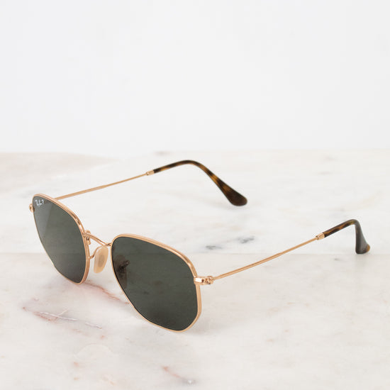 Gold-framed sunglasses with dark lenses on a marble surface