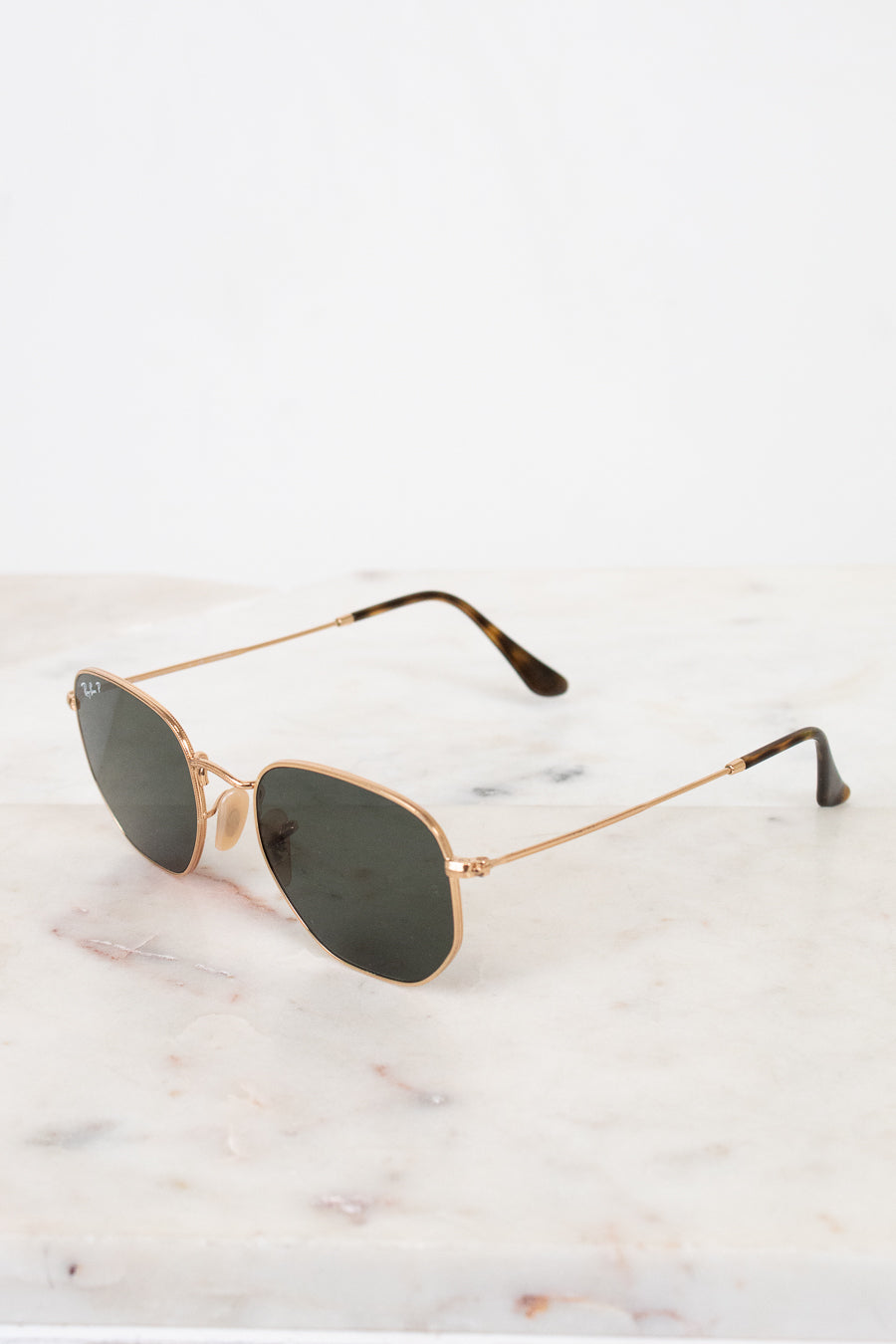 Gold-framed sunglasses with dark lenses on a marble surface