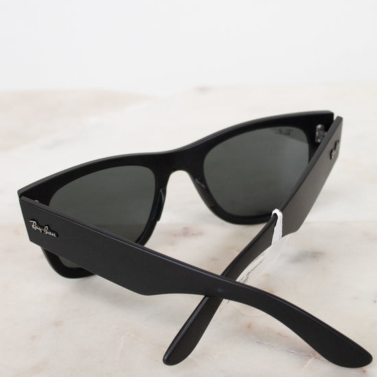 Black sunglasses with a Ray-Ban logo on a light marble background
