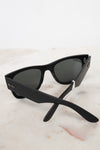 Black sunglasses with a Ray-Ban logo on a light marble background