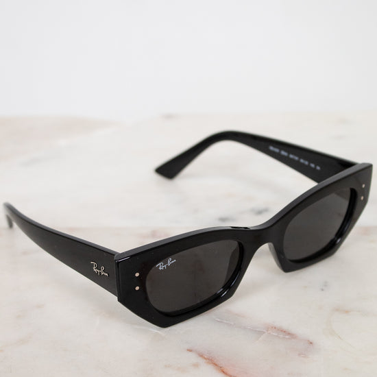 Black sunglasses with a Ray-Ban logo on a marble surface