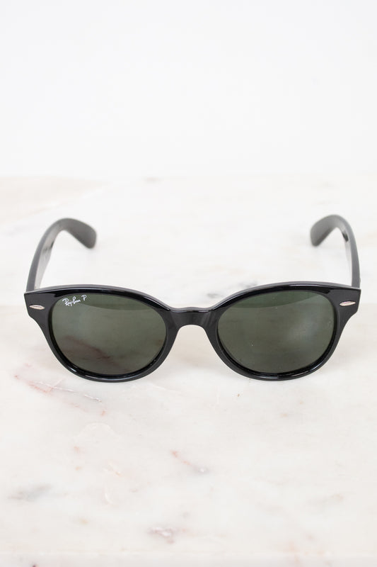 Black sunglasses with black lenses on a white marble surface