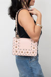 Person wearing a pink studded handbag on a plain background
