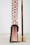 Pink handbag with decorative strap on a white background