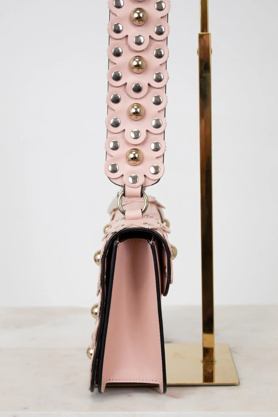 Pink handbag with decorative strap on a white background