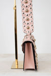 Pink handbag with decorative strap on a white background