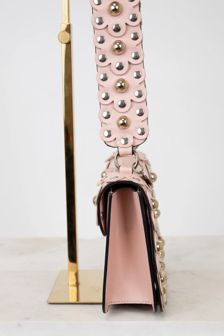 Pink handbag with decorative strap on a white background
