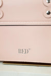 Close-up of a pink handbag with 'RED' branding on a light background