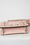Pink handbag with decorative studs on a white background