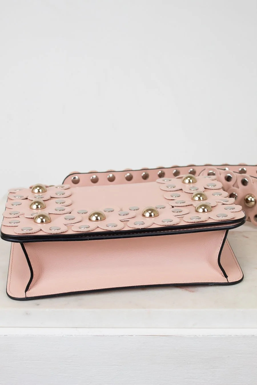 Pink handbag with decorative studs on a white background