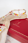 A pair of beige Rene Caovilla flat sandals decorated with colorful flowers and white lace trim, displayed on top of a red branded shoebox.