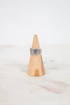 Silver ring on a wooden cone against a white background