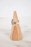 Silver ring on a wooden cone against a white background