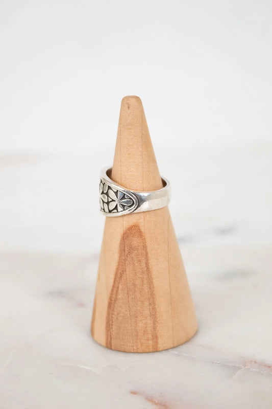 Silver ring on a wooden cone against a white background
