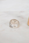 Silver ring with intricate design on a light marble surface