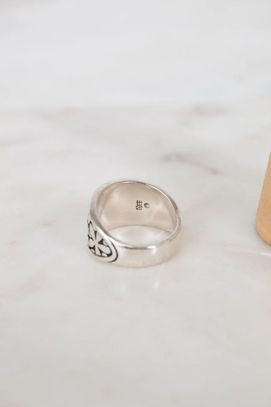 Silver ring with intricate design on a light marble surface
