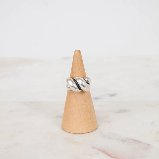 Silver ring on a wooden cone against a marble background