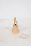 Silver ring on a wooden cone against a marble background