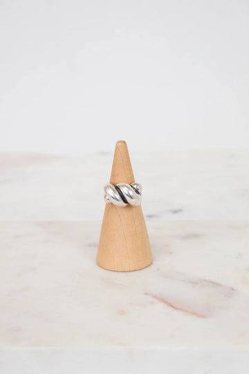 Silver ring on a wooden cone against a marble background