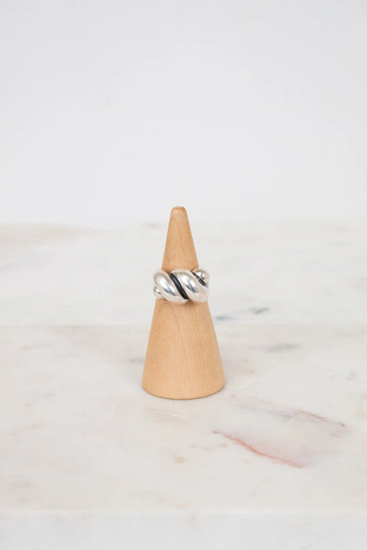 Silver ring on a wooden cone against a marble background