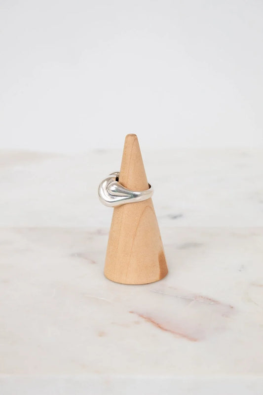 Silver ring on a wooden cone against a white background