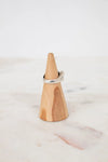 Wooden ring holder with a silver ring on a marble surface