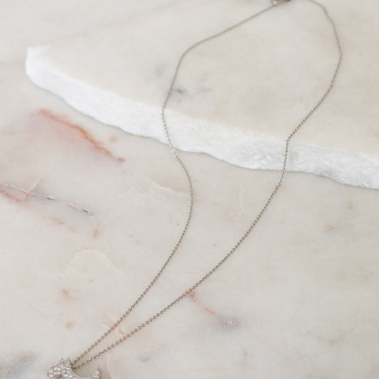 Necklace with a dog-shaped pendant on a marble surface