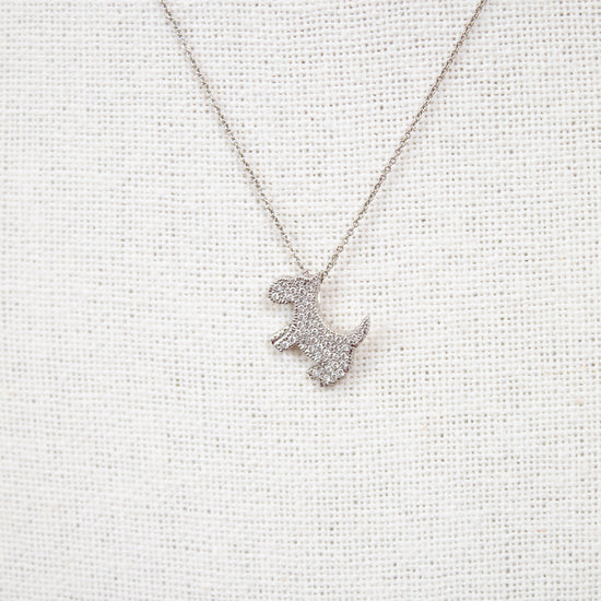 Silver necklace with a dog-shaped pendant on a light gray textured background