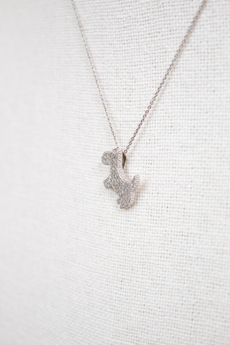 Silver necklace with a small pendant on a light gray background