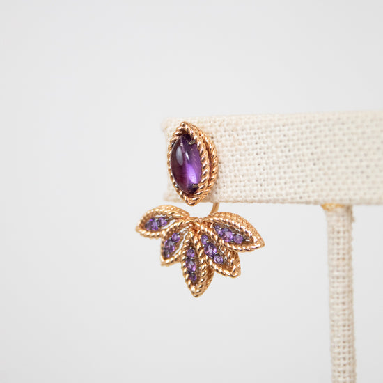 Gold earring with purple gemstones on a white background