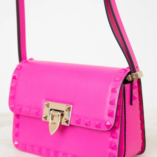 Pink handbag with gold accents on a light background