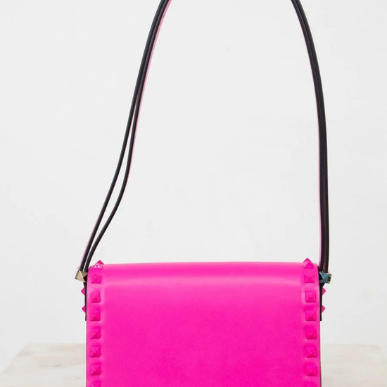 Pink handbag with black strap on a white background