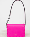 Pink handbag with black strap on a white background