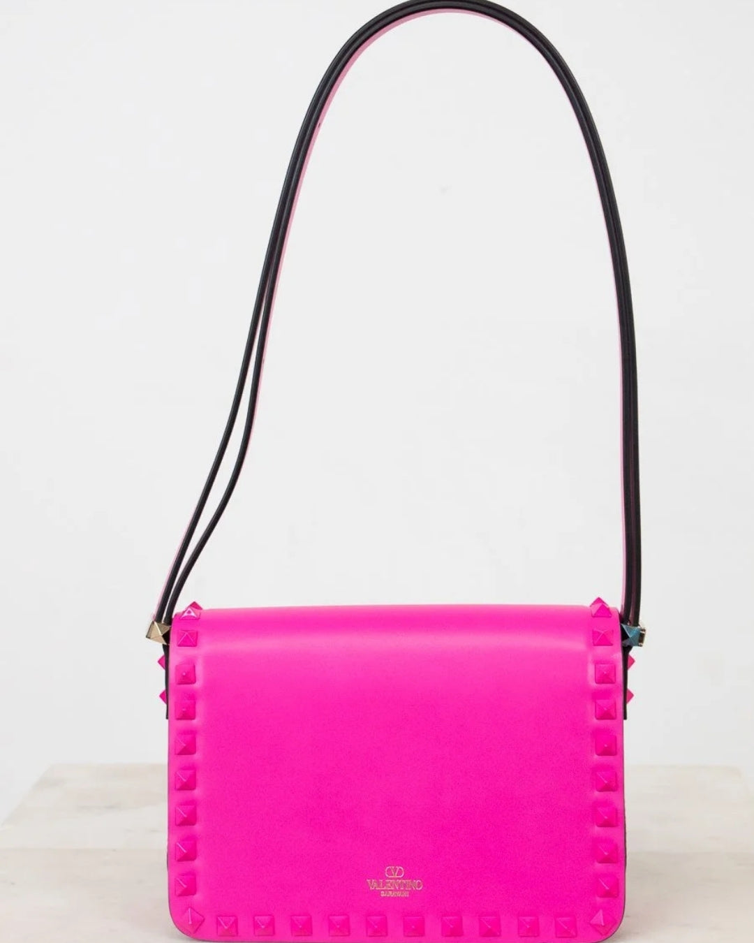 Pink handbag with black strap on a white background