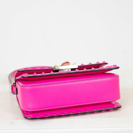Pink handbag with studded details on a light gray background