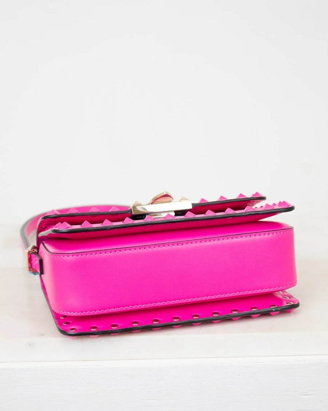 Pink handbag with studded details on a light gray background