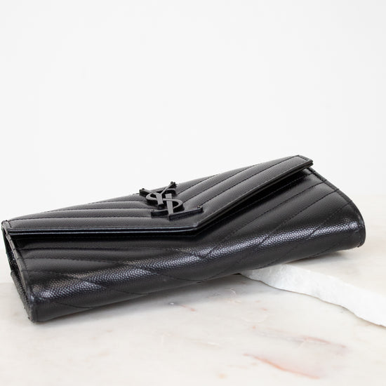 Black quilted wallet on a white marble surface