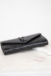 Black quilted wallet on a white marble surface