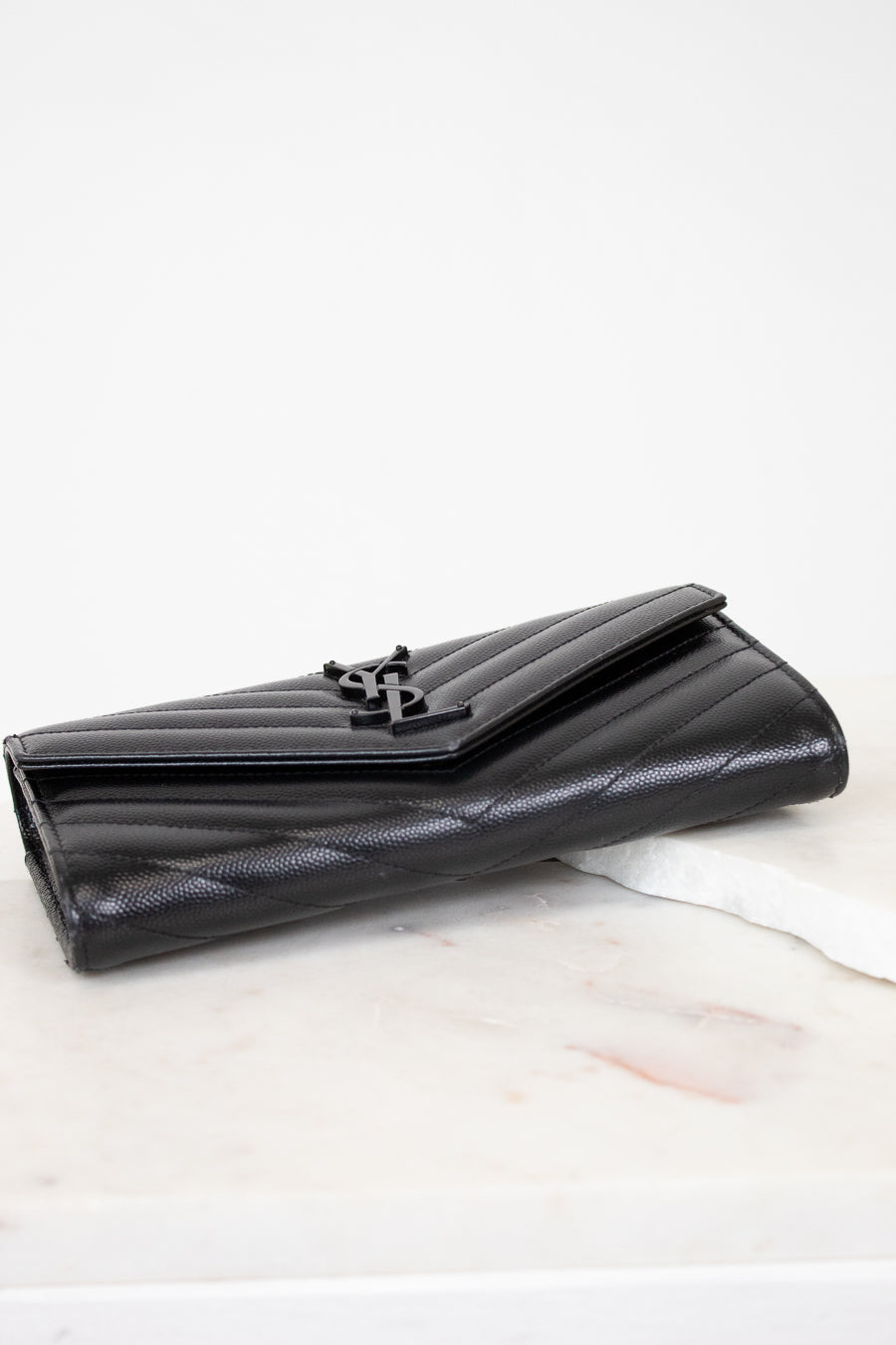 Black quilted wallet on a white marble surface