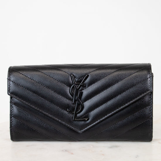Black quilted wallet with a brand logo on a light marble background