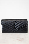 Black quilted wallet with a brand logo on a light marble background