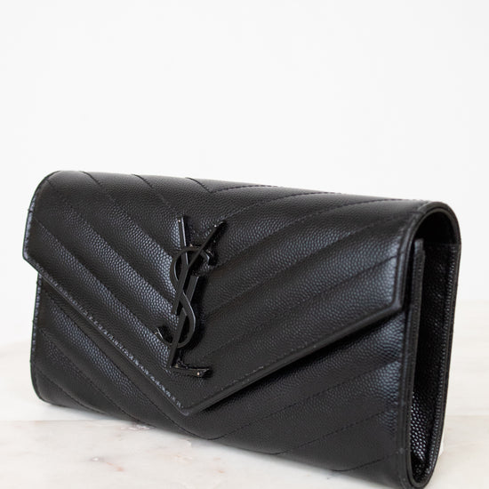 Black quilted wallet bag on a light marble surface