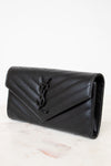 Black quilted wallet bag on a light marble surface