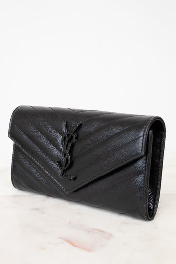 Black quilted wallet bag on a light marble surface